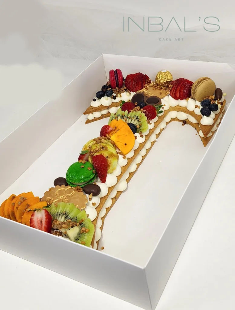 עוגת מספרים בצורת T עם פירות מעל וקצפת בשכבות