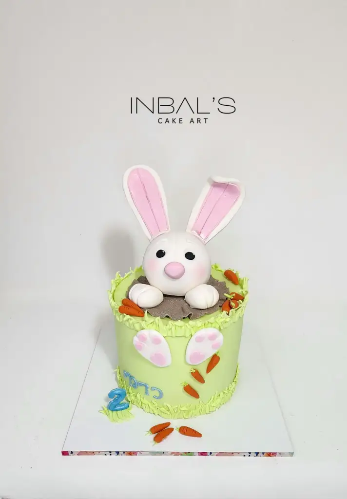 עוגה מעוצבת בצבע ירוק עם ארנב מציץ מלמעלה מבצק סוכר אכיל ליום הולדת 