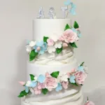 עוגות חתונה לבנה עם פרחים אכילים ורודים תכלת ועלים ירוקים שלוש קומות