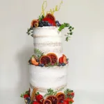 עוגה מעוצבת בשלוש קומות, מקושטת בפירות טריים, צמחייה ורשומת "אהבה" עליונה.