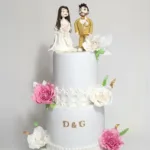 עוגת חתונה מעוצבת עם דמויות כובעות, פרחים וקישוטים, מתאימה לאירועים מיוחדים בירושלים.