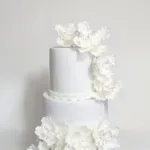 עוגה מעוצבת לבנה עם פרחים, מושלמת לאירועים כמו חתונה או יום הולדת. עיצוב אלגנטי וייחודי.